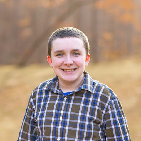 Jacob Landman smiling outdoors in a plaid shirt